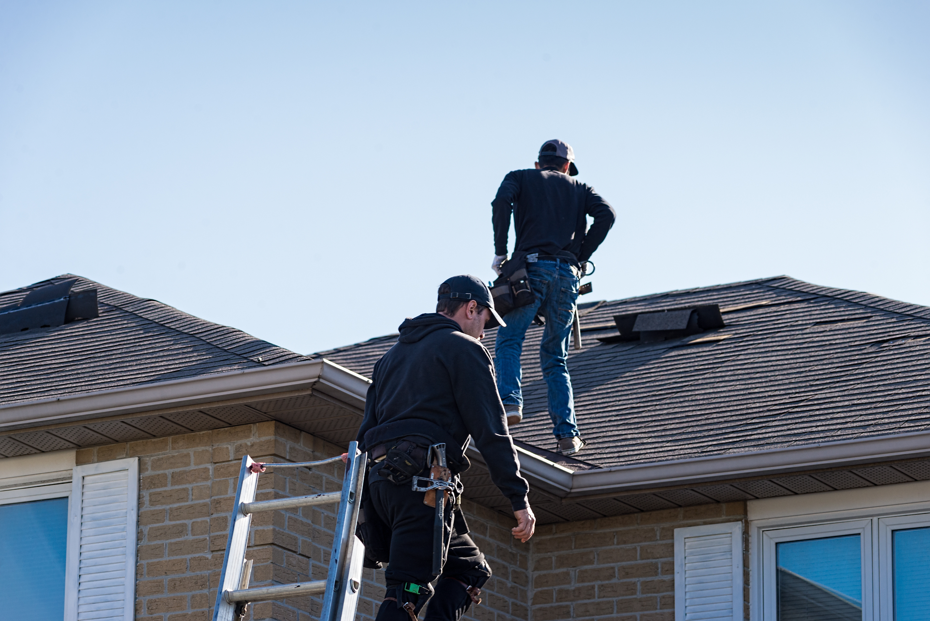 Roofing crew treating an aging asphalt-shingle roof to extend its life
